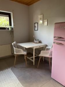 cocina con mesa, sillas y nevera rosa en Haus Anna, en Lemberg