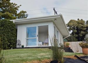 a small white house with a large window at Minden Meadows Retreat in Tauranga