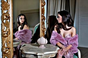 una mujer con un vestido púrpura sentada frente a un espejo en Kèramos Luxury Rooms, en Sciacca