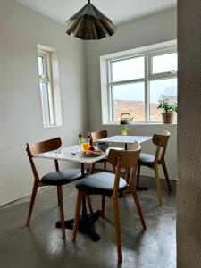 einen Tisch und Stühle in einer Küche mit einem Tisch und einem Fenster in der Unterkunft Lindarhóll Guesthouse in Stóri-Bakki