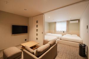 a hotel room with two beds and a couch at Hotel Ninestates Kagoshima in Kagoshima