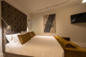 een slaapkamer met een groot wit bed en een televisie bij Hotel Arancioamaro in Cannero Riviera