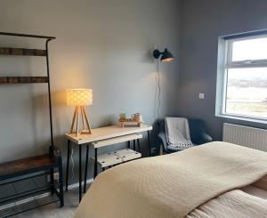 a bedroom with a bed and a desk with a lamp at Lindarhóll Guesthouse in Stóri-Bakki