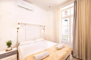 um quarto branco com uma cama e uma janela em Apartamentos Turísticos Gran Vía em Cartagena