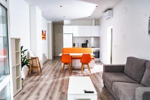 uma sala de estar com um sofá e cadeiras laranja em Apartamentos Turísticos Gran Vía em Cartagena