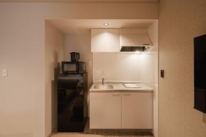 鹿児島市にあるホテル ナインステイツかごしまの白い小さなキッチン(シンク、電子レンジ付)