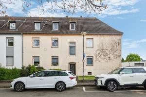 Deux voitures garées sur un parking en face d'une maison dans l'établissement Worker Apartment Kleve, à Clèves