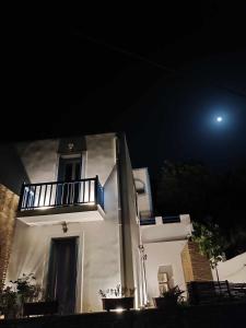 a white house with a balcony at night at Andros Guesthouses in Andros