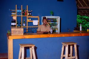 mężczyzna siedzący w barze z dwoma drewnianymi stołkami w obiekcie The Better Inn w mieście Moshi