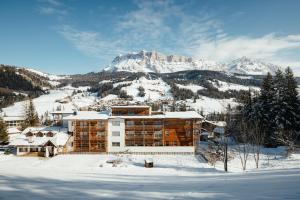 un edificio en la nieve frente a una montaña en Hotel Melodia del Bosco en Badia