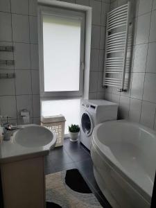 biała łazienka z pralką i wanną w obiekcie Senvages nuoma w Kłajpedzie