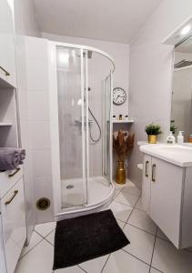 uma casa de banho branca com um chuveiro e um lavatório. em Le Coqu'Aix - Hyper-Centre - Parking - Wifi - Netflix em Aix-les-Bains