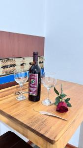 Una botella de vino y dos copas en una mesa de madera. en hostal Balcon de Piedra, en Urubamba