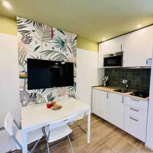a kitchen with a white table and a tv on a wall at Le Palme Village in Terracina