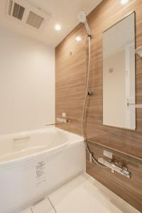 a bathroom with a white tub and a mirror at Hotel Ninestates Kagoshima in Kagoshima