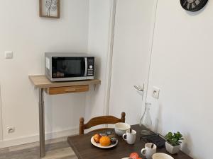 a microwave sitting on a table with a plate of fruit at Studio Aix-les-Bains, 1 pièce, 2 personnes - FR-1-617-23 in Aix-les-Bains