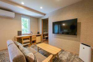 a living room with a couch and a tv on a wall at Little Grebe in Chino