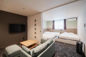 a hotel room with two beds and a tv at Hotel Ninestates Kagoshima in Kagoshima