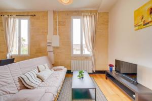 Una sala de estar con un sofá y un televisor. en Le Yellow - Centre de Bordeaux, en Burdeos