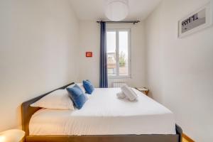 Un dormitorio con una gran cama blanca con almohadas azules. en Le Yellow - Centre de Bordeaux, en Burdeos