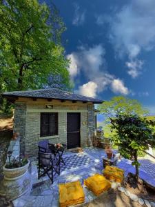 een stenen huis met een patio met een tafel en stoelen bij The Mushroom Cottage in Anilio Pelion