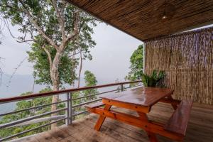 een houten tafel en bank op een balkon met een boom bij Romhaey Kirirom Resort in Kampong Seila