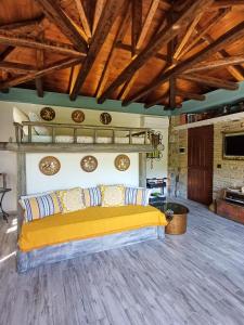 Un dormitorio con una cama amarilla en una habitación con techos de madera. en The Mushroom Cottage en Anilio Pelion