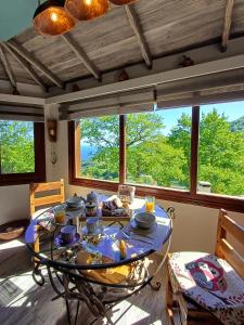 een eetkamer met een glazen tafel voor een raam bij The Mushroom Cottage in Anilio Pelion
