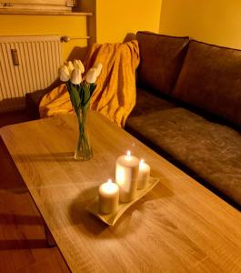 a table with a vase of flowers and candles on it at Apartament Rondo AC Progres in Toruń