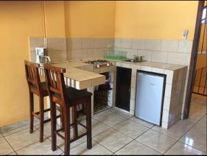 a kitchen with a sink and a counter with two chairs at Hotel central in San Juan del Sur