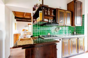 - une cuisine avec des murs carrelés verts et des placards en bois dans l'établissement Villa Teresa - Villa & Piscina immersi nel vigneto!, à Montecalvo Versiggia