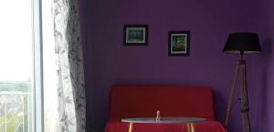 Camera viola con divano rosso e tavolo di Lumineux et proche de tout avec balcon et à côté du bois a Boulogne-sur-Mer