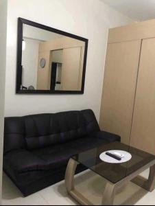 sala de estar con sofá negro y espejo en Field Residences Condotel Near Airport, en Manila