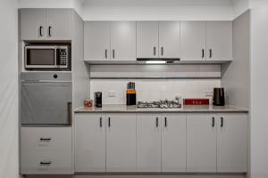 uma cozinha com armários brancos e um micro-ondas em Exclusive Stays - Southgate em Melbourne