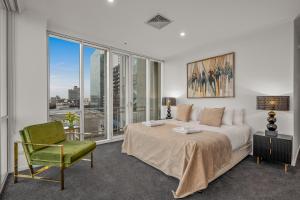 a bedroom with a large bed and a green chair at Exclusive Stays - Southgate in Melbourne +22 photos