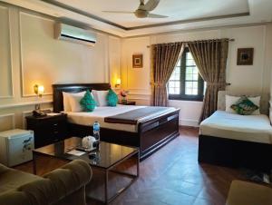 uma sala de estar com duas camas e um sofá em Riviera Courtyard Guest House Islamabad em Islamabad