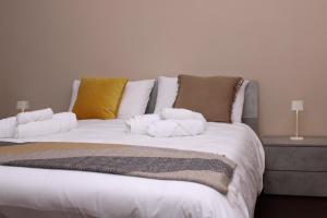 Una cama grande con almohadas blancas encima. en JOHN'S ROOMS, en Villa D'agri