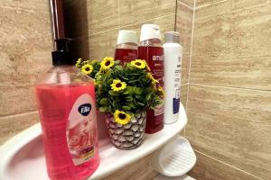 a bathroom sink with four bottles and flowers on it at Beautiful Salalah Beach Apartments - 1 by Beautiful Salalah Tours in Salalah +107 photos