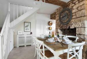 een eetkamer met een tafel en een stenen muur bij A beautiful Cotswolds Cottage in Stroud in Stroud