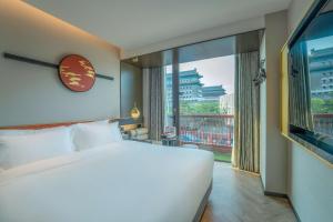 ein Schlafzimmer mit einem großen Bett und einem großen Fenster in der Unterkunft M Hotel - Beijing Tiananmen Square Qianmen Subway Station in Peking