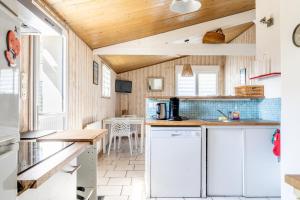 a kitchen with white cabinets and a wooden ceiling at Maison de pêcheur au calme in La Faute-sur-Mer +15 photos