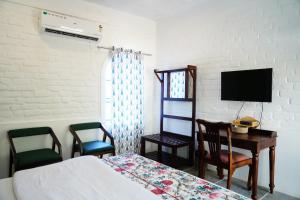 Schlafzimmer mit einem Bett, einem Schreibtisch und einem TV in der Unterkunft Heli Pushkar in Pushkar