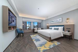 1 dormitorio con 1 cama blanca grande y TV en Liz Hotel Maoming Dianbai, en Maoming