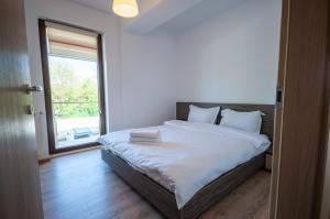um quarto com uma cama grande e uma janela grande em Snagov Lake Apartments - Club Lac Snagov em Turbaţi