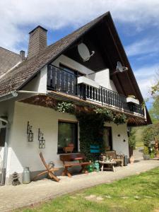 een huis met een balkon en een tafel en banken bij Gasthof Walhalja in Schmallenberg