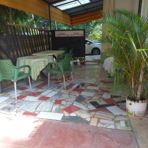 a patio with green chairs and tables on a tiled floor at Zaradise Suites in Mombasa