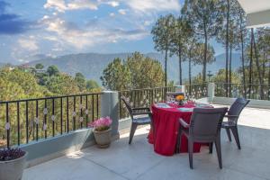 a table and chairs on a balcony with a view at The Mill Family suit , 3beds in Kasauli