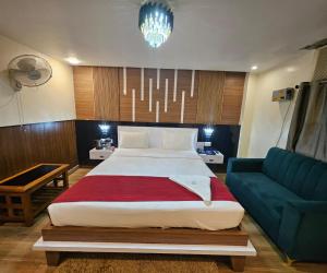 a bedroom with a large bed and a blue couch at HOTEL Bodhi Tree in Patna