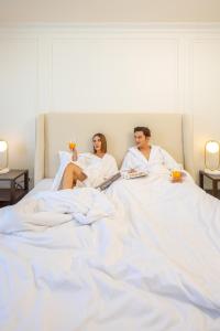 mężczyzna i kobieta leżący w łóżku z drinkami w obiekcie Olivia Boutique Thailand w mieście Ban Bang Kraba