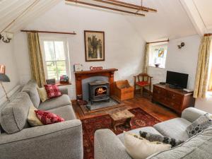 a living room with two couches and a fireplace at Penyrallt Fach Cottage in Llandysul